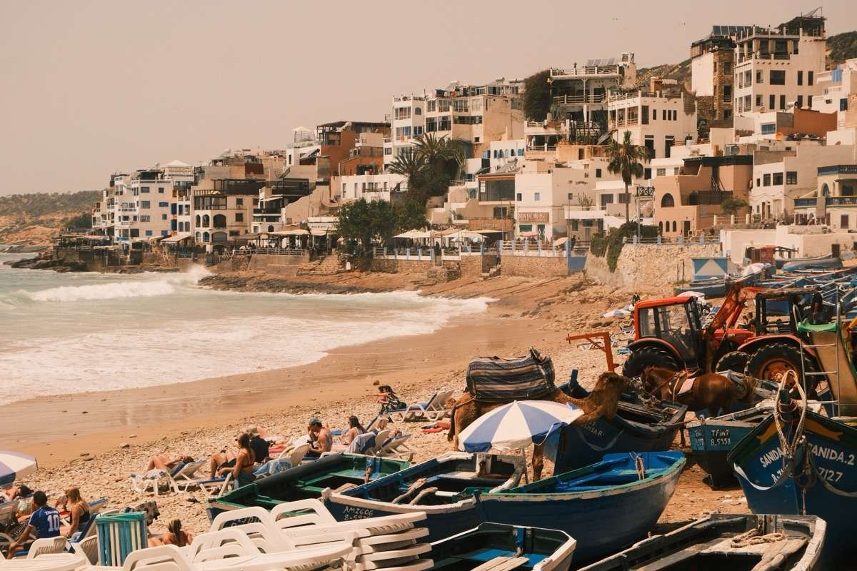 Beachfront with fishing boats and visitors in Taghazout, Morocco