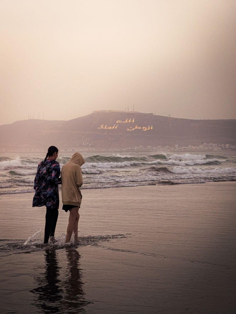 Two people walking on Agadir beach at dusk