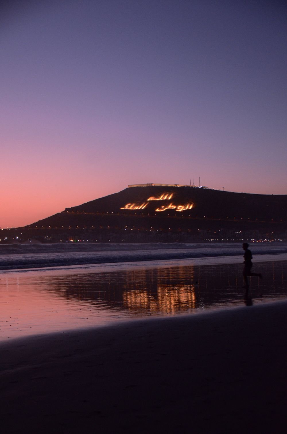 Atardecer en la playa de Agadir con la inscripción de la colina iluminada