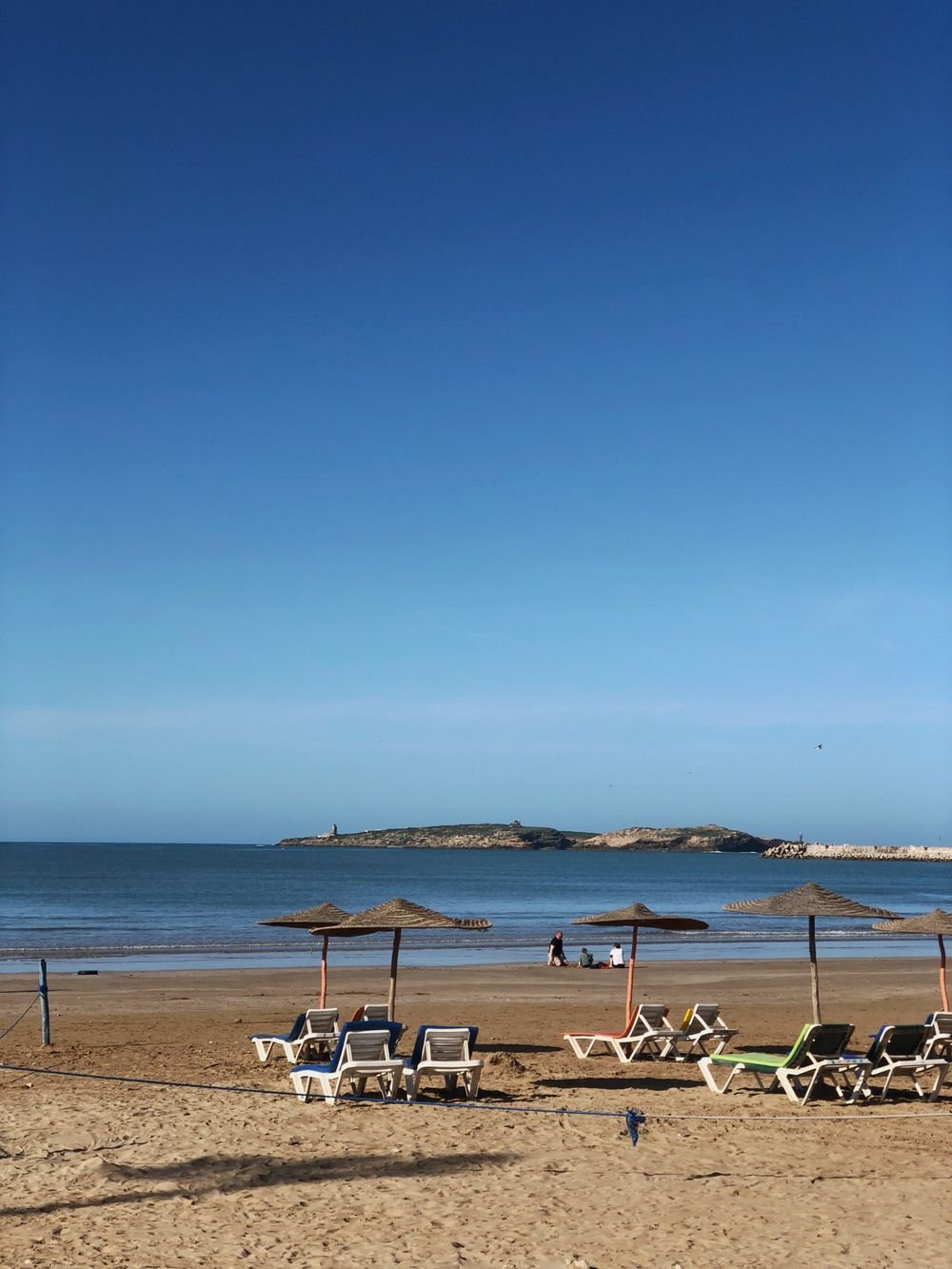Sun loungers and straw parasols on a calm Moroccan beach