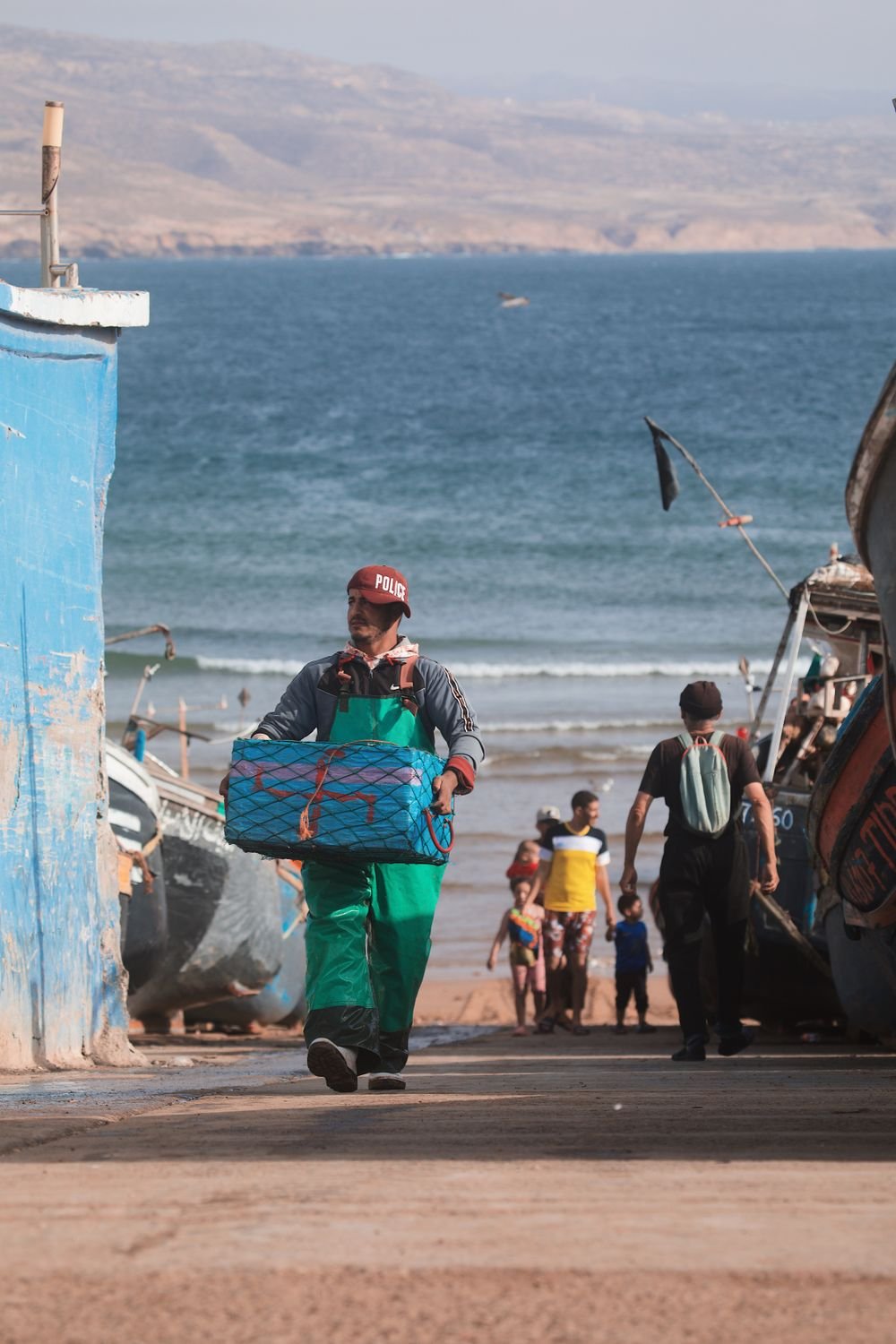 A fisherman carrying a crate of fish up the steps from the beach