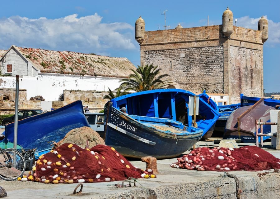 Blue fishing boats and red nets below the old sea bastion in Essaouira