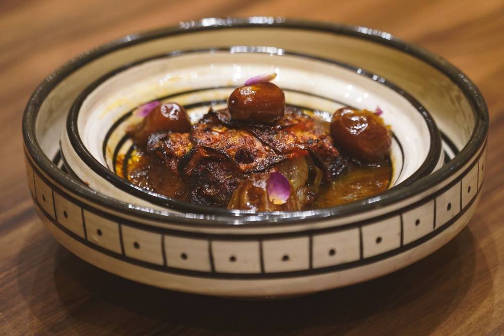 Tajine con dátiles servido en un plato de cerámica pintado a mano