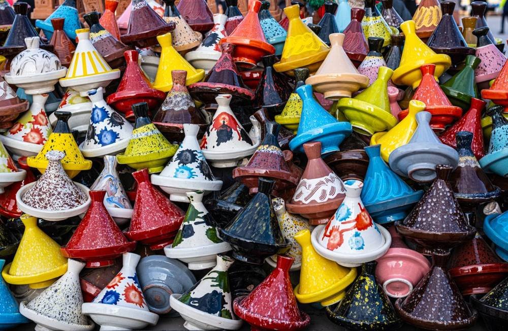 Piles de tajines émaillés colorés sur un marché marocain