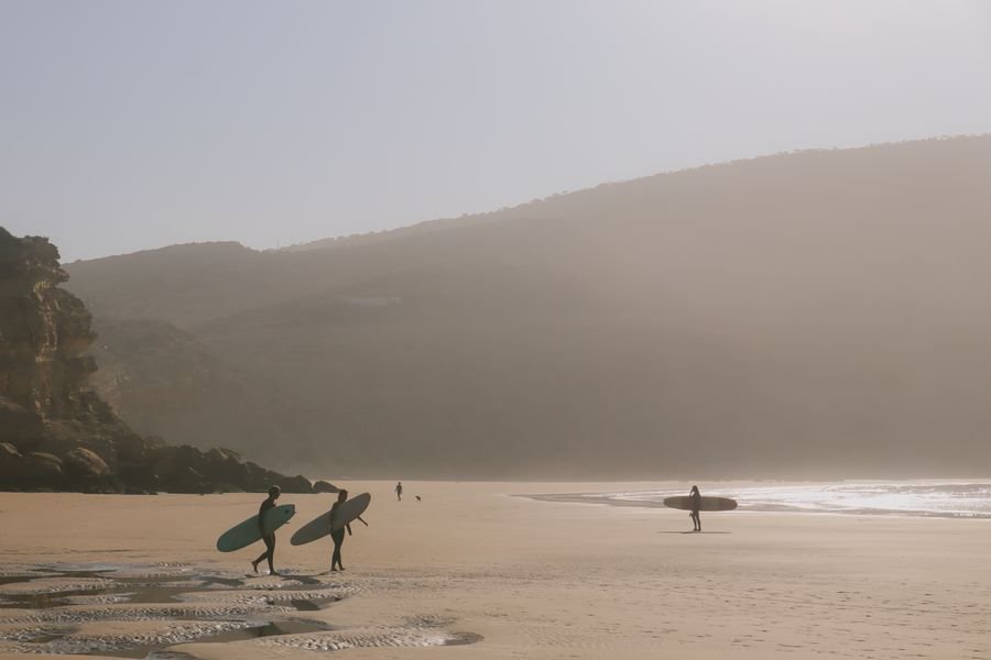 Surfistas caminando por la playa de Imsouane al atardecer