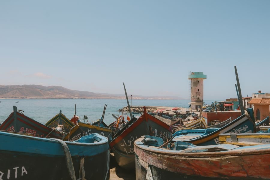 Coloridas barcas de pesca en la playa de Imsouane con la torre del puerto