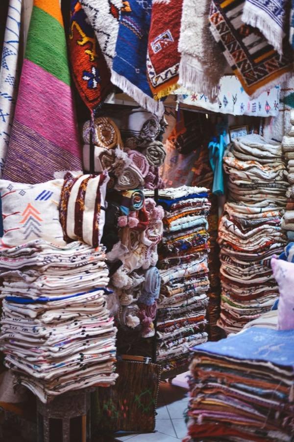 Rugs and textiles stacked at a stall in the Agadir souk