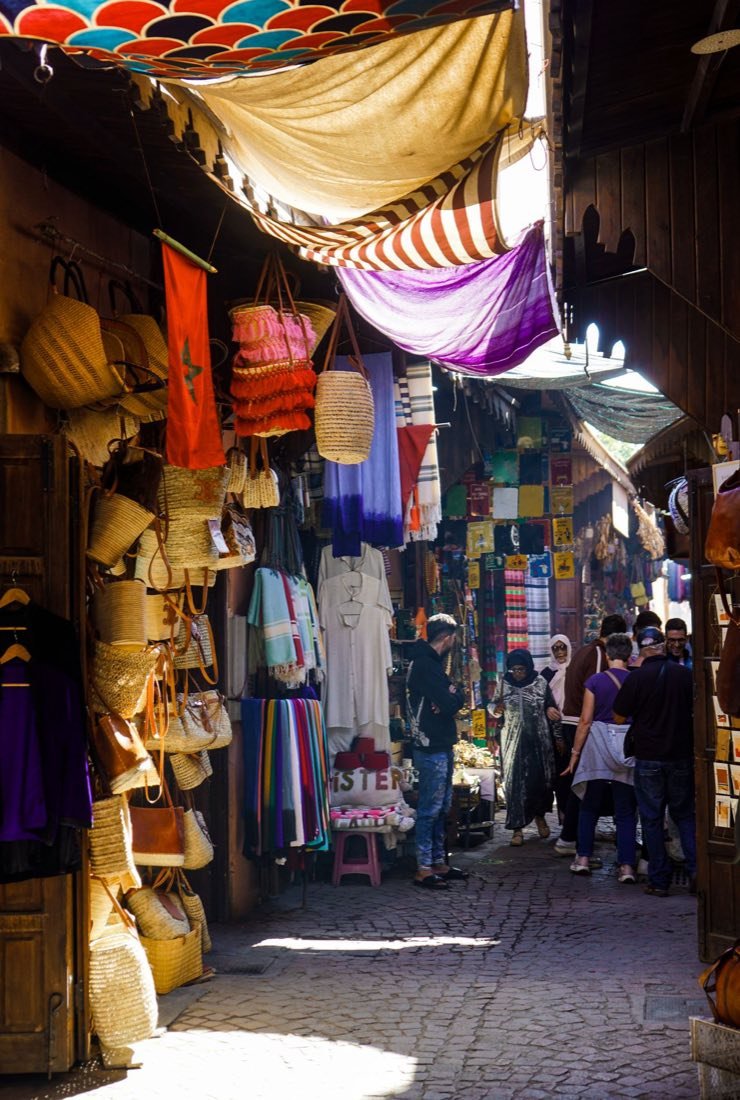A covered souk alley hung with textiles and baskets