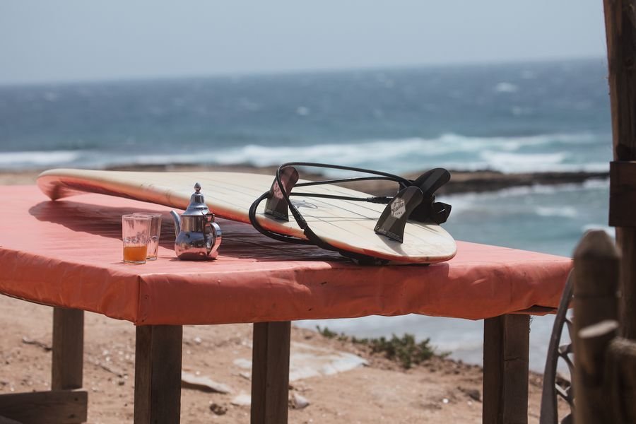 Surfboard and a glass of mint tea on a table above the Atlantic