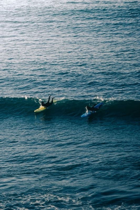 Two surfers paddling into a wave on the Atlantic coast of Morocco
