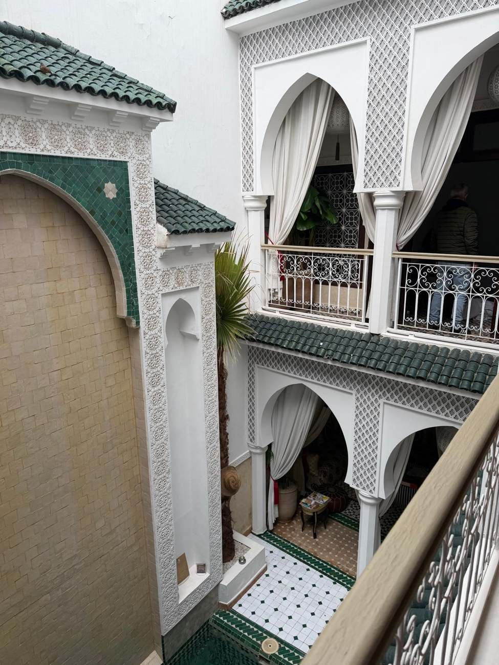 Stuc blanc, zellige vert et balcons dans un riad marocain