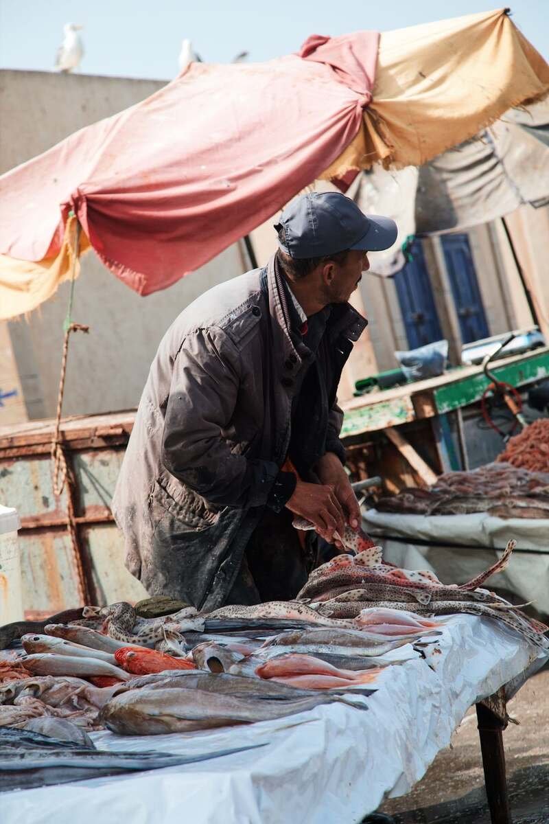 A fish vendor at his stall under a parasol