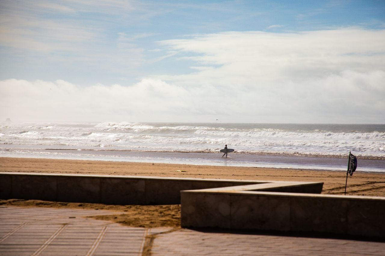 Un surfista camina con su tabla por una playa atlántica de Marruecos