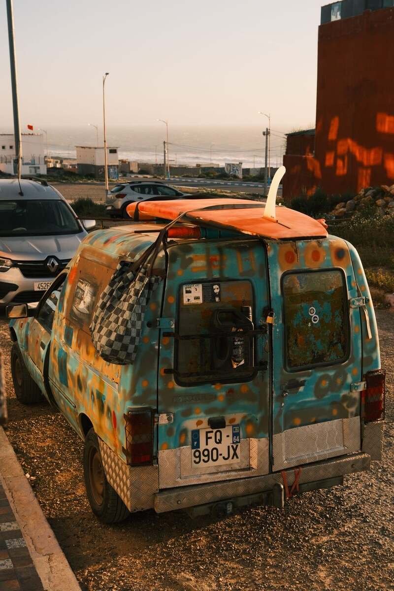 A painted van with surf gear parked by the coast at dusk