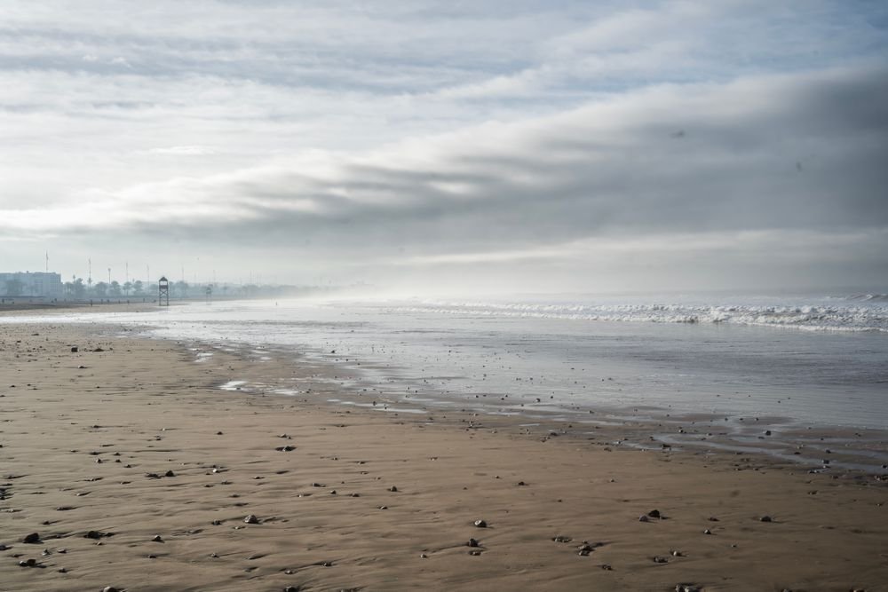A misty, overcast morning on a quiet beach with wet sand