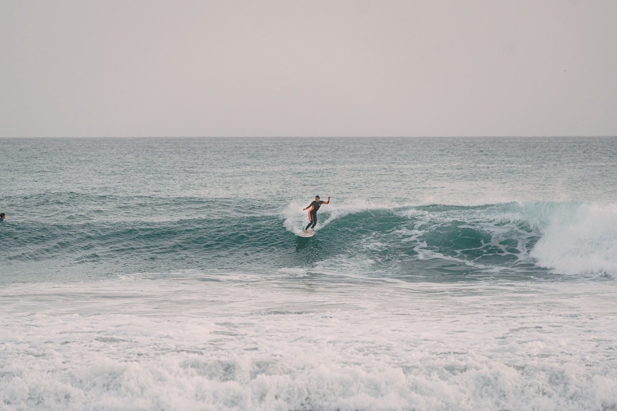 Surfeur en combinaison sur une vague à Taghazout, côte atlantique du Maroc