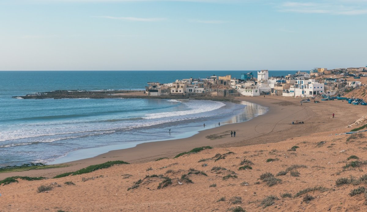 Plage atlantique avec village côtier blanc, Tifnit, Maroc
