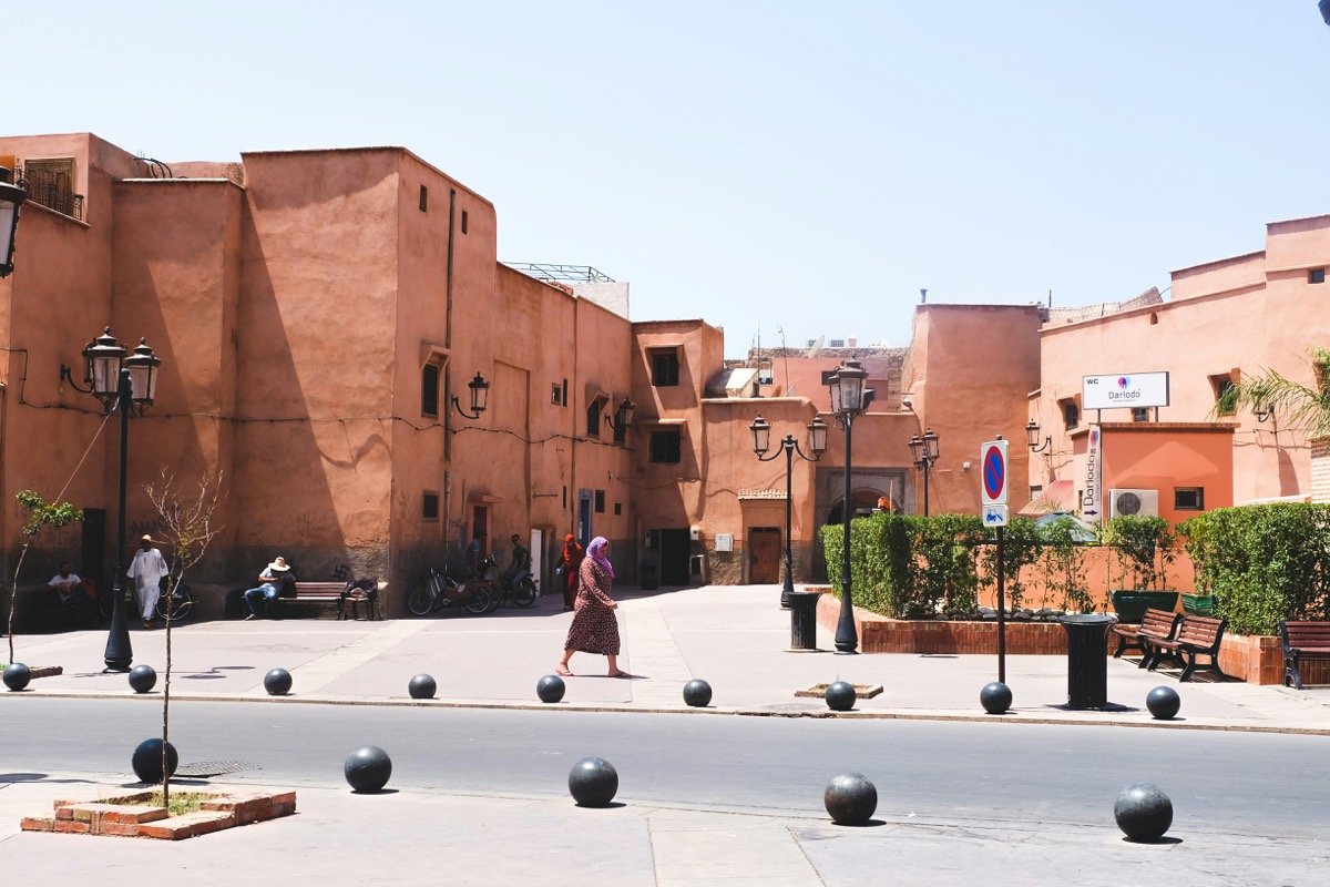 Sunlit Moroccan town square with traditional red ochre buildings in Marrakech