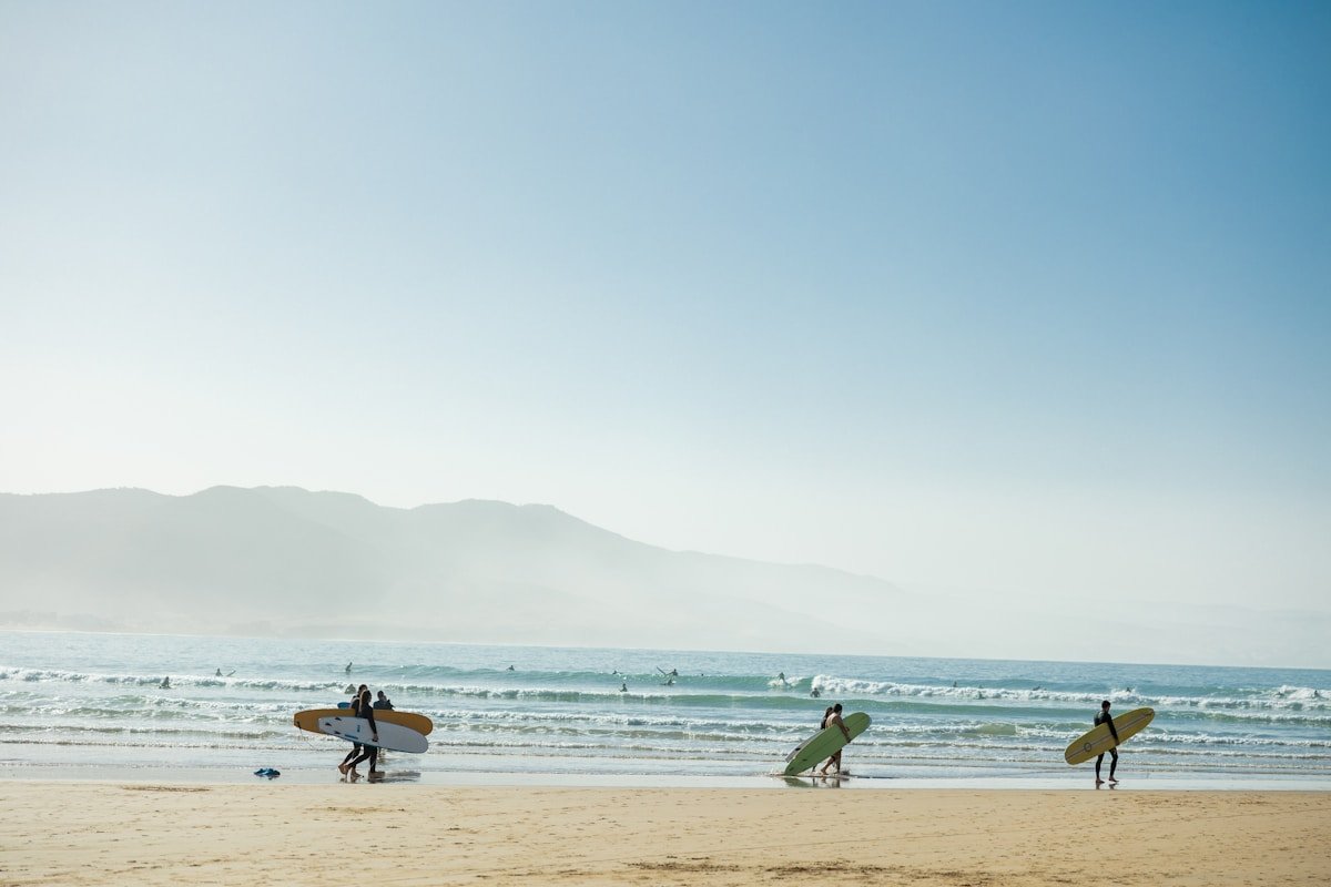 Group of surfers carrying boards on the beach at Imsouane, Morocco