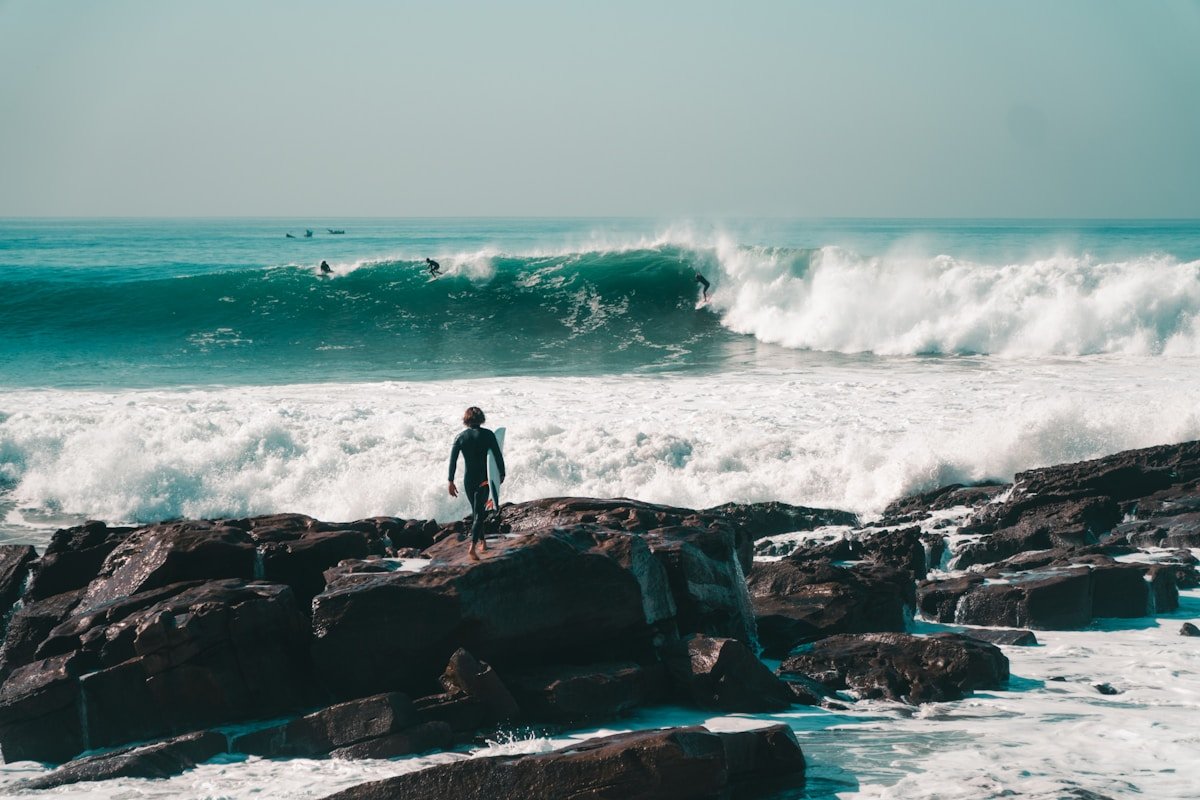 Man on rocks looking out at ocean swell at Anchor Point, Taghazout