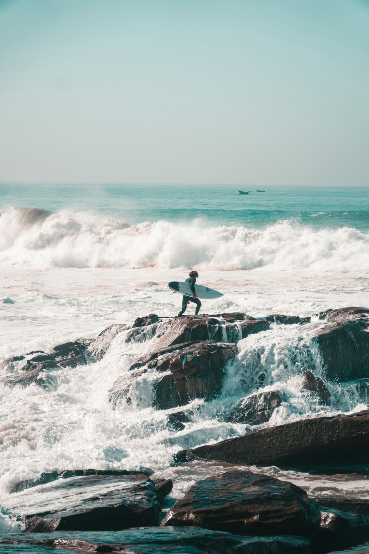 Surfer with board on rocks at Anchor Point surf spot, Morocco