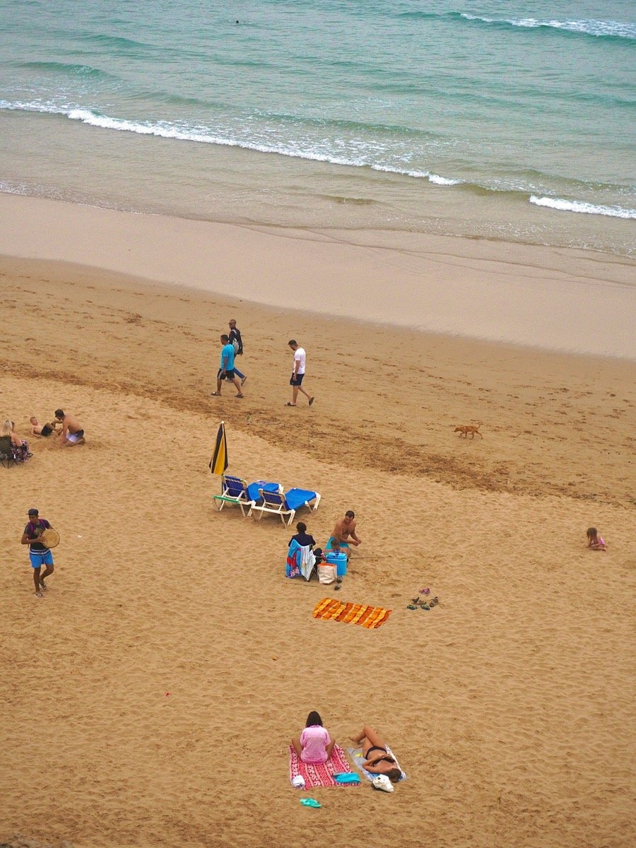 Families relaxing on a sandy Moroccan beach with calm Atlantic waves
