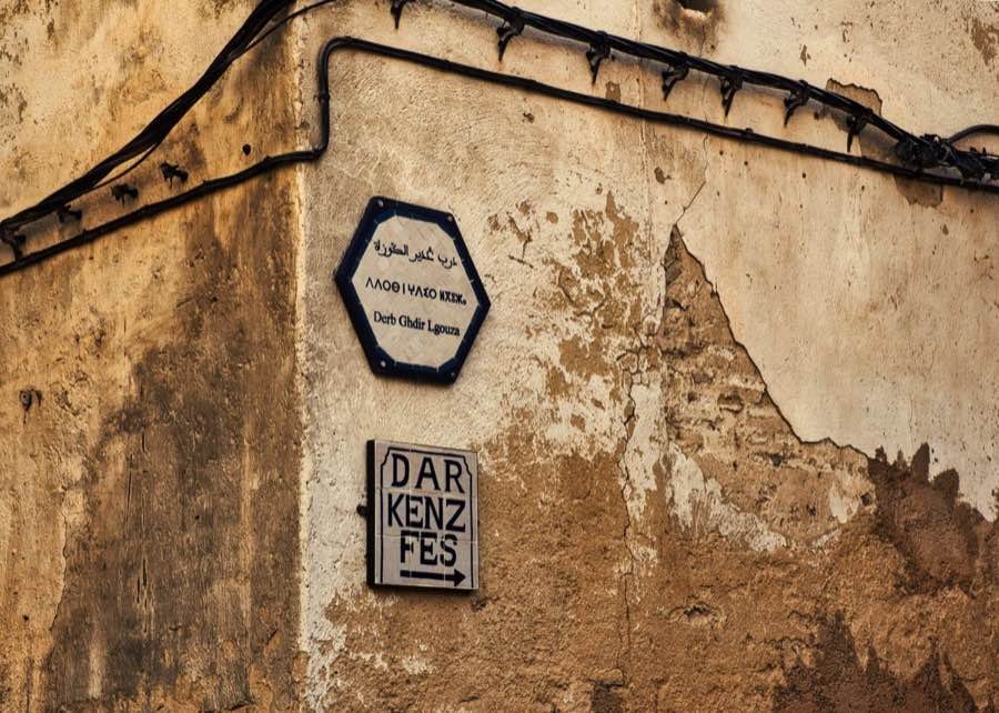 Tile street signs in Arabic, Tifinagh and Latin script on a medina wall in Fes, Morocco