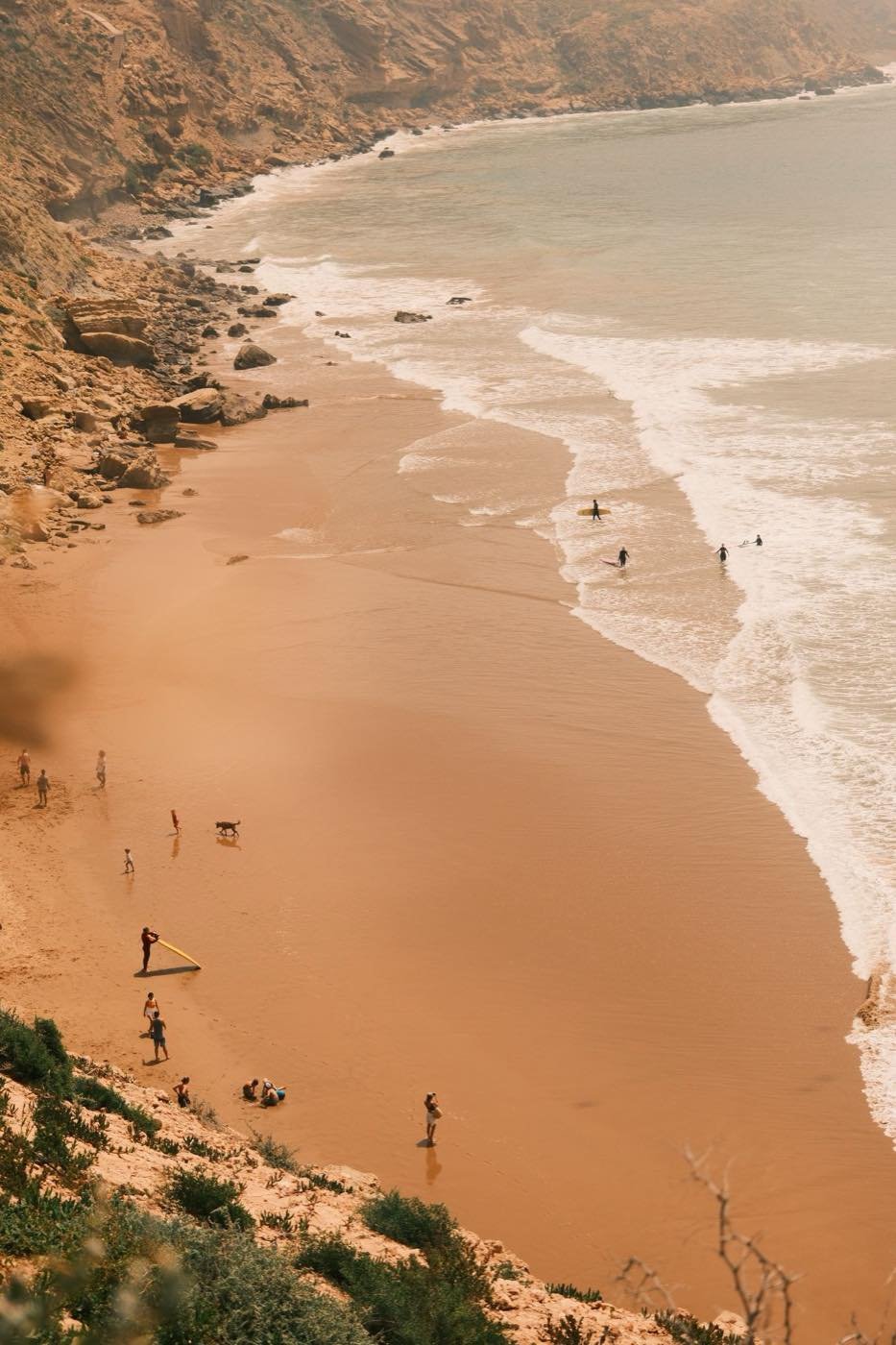 Surfers and rocky cliffs on a beach on Morocco's Atlantic coast